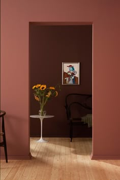 a vase filled with yellow flowers sitting on top of a wooden floor next to a chair