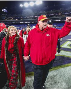 a man and woman walking on the field at a football game