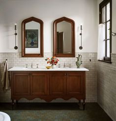 a bathroom with two sinks and mirrors on the wall