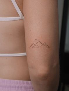 a woman's arm with a tattoo on the left side of her body and mountains in the background