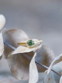 The round bicolor green sapphire was mined in the Songea, Tanzania, and hasn't been heated or treated. The 18 karat yellow gold band brings out the sapphire's warmer tones and magnifies its gorgeous gleams. Each piece of our jewelry is handcrafted with love. Gold Sapphire Ring With Smooth Bezel, Gold Yellow Sapphire Round Ring, Gold Round Yellow Sapphire Ring, Gold Yellow Sapphire Ring, Round, Everyday Yellow Gold Solitaire Emerald Ring, Green Sapphire Round Ring, Fine Jewelry 14k Gold Green Sapphire Ring, Green Sapphire Ring With Bezel Setting As Gift, Gift Yellow Gold Sapphire Ring With Smooth Bezel