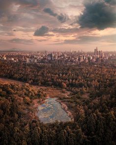 an aerial view of a city and lake in the foreground, surrounded by trees