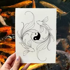 a person holding up a card in front of some koi carps and goldfish