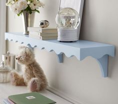 a teddy bear is sitting on a shelf next to books and a vase with flowers