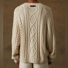 the back of a man wearing a white cable knit sweater