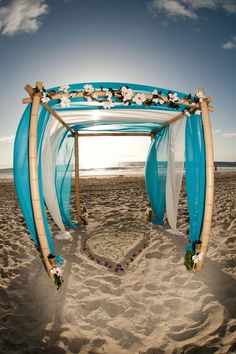 an arch decorated with flowers and ribbons on the beach