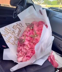 a bouquet of pink roses sitting in the back seat of a car with a happy birthday sign on it