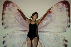 a woman standing in front of a giant butterfly