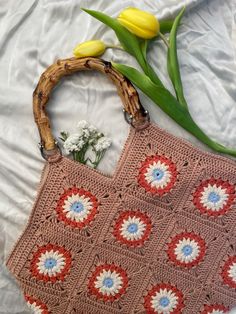 In the photo there is a brown crochet bag with granny squares in blue and white. The bag has bamboo handles. There are also some flowers. Crochet Granny Square Tote Bag, Granny Square Tote Bag, Granny Square Tote