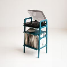 an old record player on top of a blue stand with records and vinyls in it