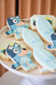 decorated cookies with cartoon characters on them sitting on a cake plate in front of a window