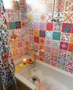 a bathtub filled with lots of foam next to a shower curtain covered in colorful tiles