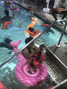 people are in an indoor swimming pool on rafts