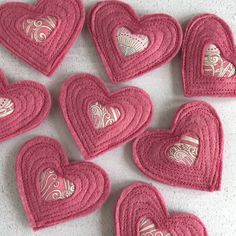 crocheted heart coasters are arranged on a table with white and pink designs