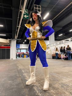 a woman dressed in costume standing next to a street sign at an indoor convention center