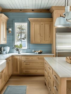 a kitchen with wooden cabinets and white counter tops in front of a blue painted wall