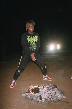 a man standing next to a fire in the dirt