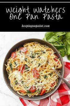 a pan filled with pasta and spinach on top of a table