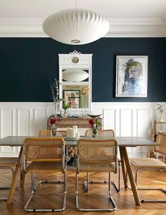 a dinning room table and chairs in front of a mirror on the wall above it