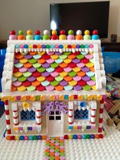 a toy house made out of legos with candy on the roof and decorations around it