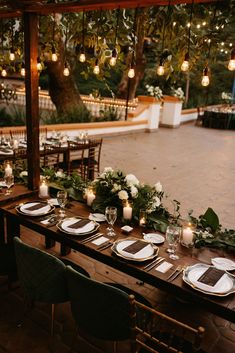 a long table with plates and place settings set for an outdoor dinner party in the evening