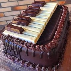 a chocolate cake with white and brown icing on it's sides, topped with an organ keyboard