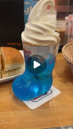 an ice cream sundae is sitting on a table next to a plate with a sandwich