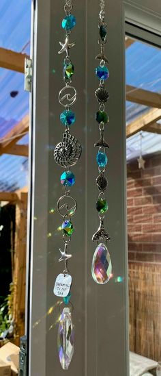 several different colored beads hanging from a glass door