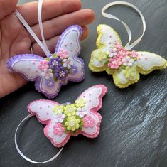 two handmade butterfly ornaments are being held by someone's hand on a table