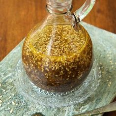 a glass bottle filled with sesame seeds sitting on top of a table next to a spoon