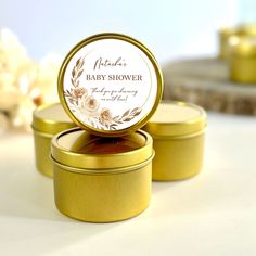 two gold tins with baby shower labels on them