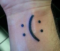 a small wrist tattoo with black dots on it