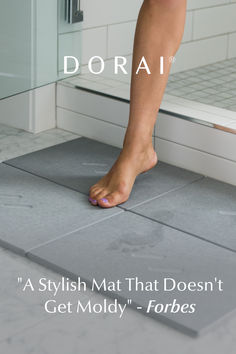 a woman's bare foot standing on a tile floor in front of a shower