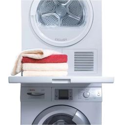 a stack of towels sitting on top of a dryer next to a washing machine