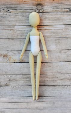 a wooden doll hanging on the side of a wood planked wall with white paint