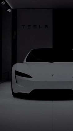 an electric car in a dark room with the word tesla on it's side