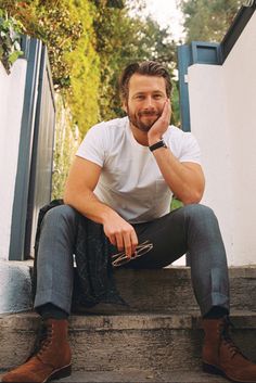 a man is sitting on the steps with his hand to his face and looking at the camera