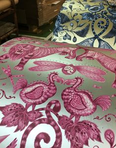 the bed is covered with pink and blue fabric, which has an intricate design on it