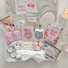 an assortment of personal care products displayed in front of a gift bag with candles and greeting cards