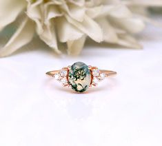 a close up of a ring on a table with flowers in the background and a white flower