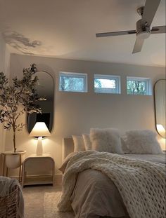 a bedroom with a bed, mirror and ceiling fan