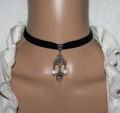 "Elastic velvet ribbon with a charming heart pendant and 2 shell pearls. The pendant is made of metal and has an antique silver color.  Length of the pendant approx. 1.57\" With lobster clasp and extension chain.   This noble choker enhances every dirndl or traditional dress. Ideal for Oktoberfest, traditional costume weddings and other festivities.   There are matching earrings in my shop.   Properties:  Metal heart, old silver-colored  Velevet ribbon black 0.62\" Shell pearls 0.236\" stainless Valentine's Day Silver Elegant Choker, Elegant Silver Heart Pendant Choker, Gothic Oc, Metal Heart, Prom Outfits, Traditional Costume, Jewelry Choker, Traditional Dress, Velvet Ribbon