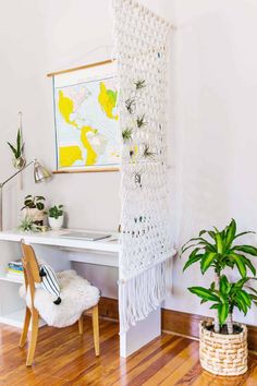 a white macrame hanging on the wall next to a desk with a potted plant