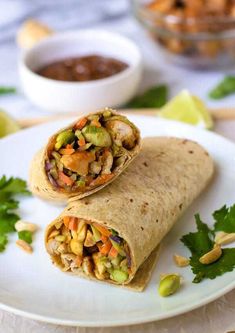 a burrito is cut in half on a white plate with cilantro and garnishes