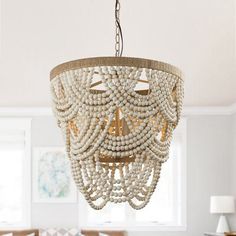 a chandelier hanging from the ceiling in a living room with white walls and furniture