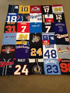 a blanket made out of baseball jerseys is on the floor in front of a carpet