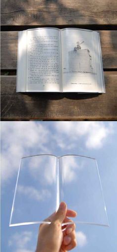 an open book sitting on top of a wooden table next to a person's hand