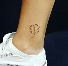 a small four leaf clover tattoo on the side of a woman's ankle,