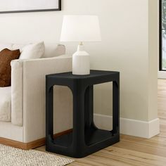 a white couch sitting next to a black table on top of a hard wood floor