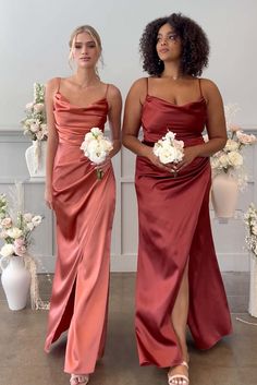 two women standing next to each other wearing dresses and holding bouquets in their hands